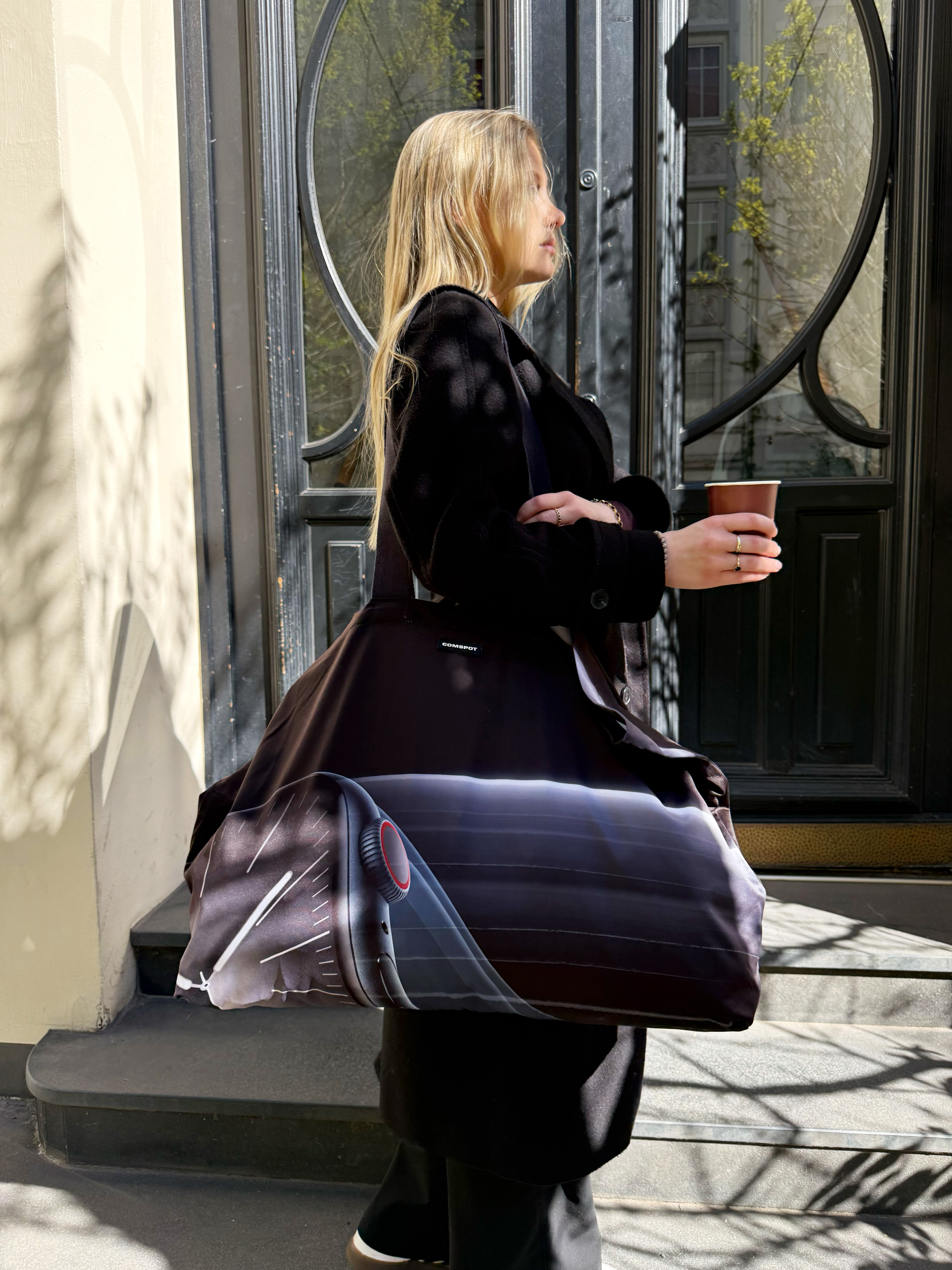 COMSPOT Upcycling Pouch in der Hand neben Kaffee und Zubehör